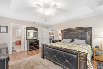 12351 Southwest 73rd Street Ocala, FL 34481 - Photo 22 of 77 a bedroom with a large bed and a chandelier