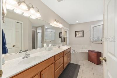 12351 Southwest 73rd Street Ocala, FL 34481 - Photo 23 of 77 a spacious bathroom with a double vanity sink a mirror and a bathtub