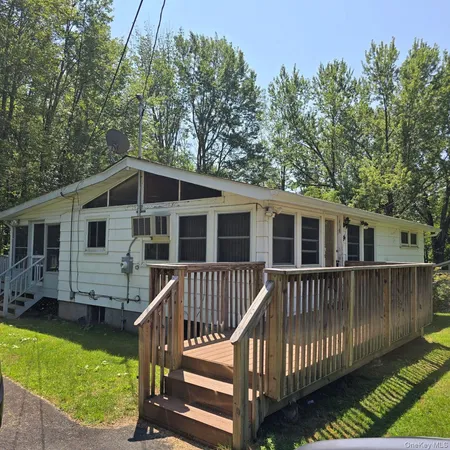 a view of a house with wooden deck and a trees in the background