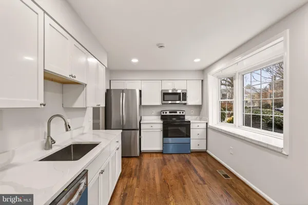 a kitchen with stainless steel appliances a sink a stove a refrigerator cabinets and a window