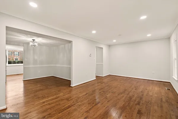 a view of an empty room with wooden floor and a kitchen
