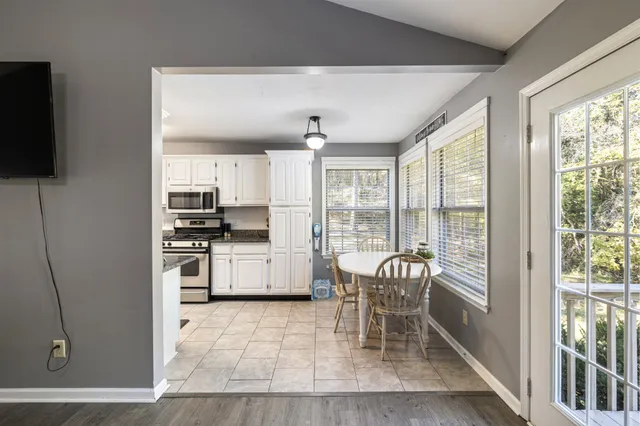 a kitchen with stainless steel appliances a stove top oven a sink a dining table and a refrigerator