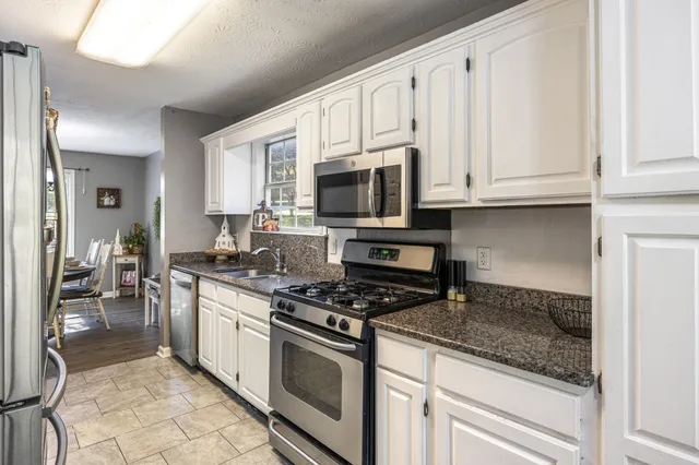a kitchen with stainless steel appliances granite countertop a stove a sink and a microwave