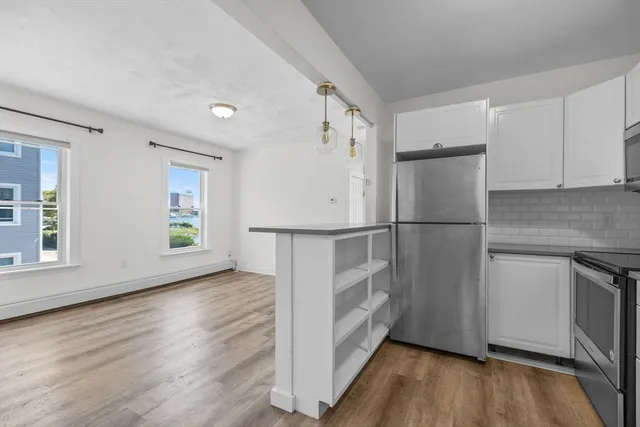 a view of kitchen with stainless steel appliances wooden floor and cabinets