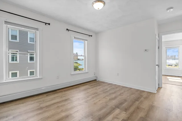 an empty room with wooden floor and windows
