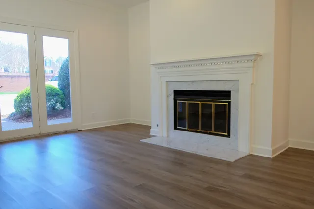 an empty room with wooden floor fireplace and windows
