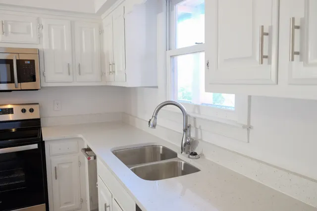 a kitchen with stainless steel appliances granite countertop a sink a stove and a microwave