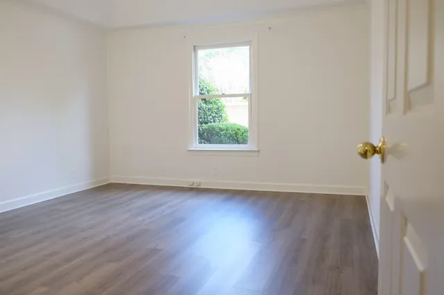 an empty room with wooden floor and a window