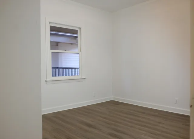 a view of an empty room with wooden floor and closet
