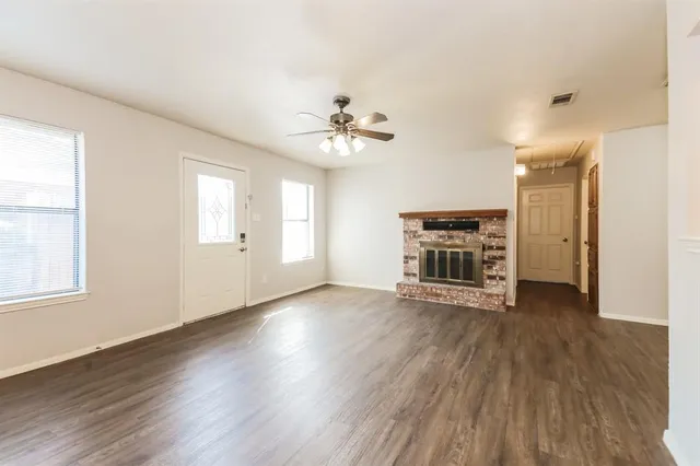 an empty room with wooden floor fireplace and windows