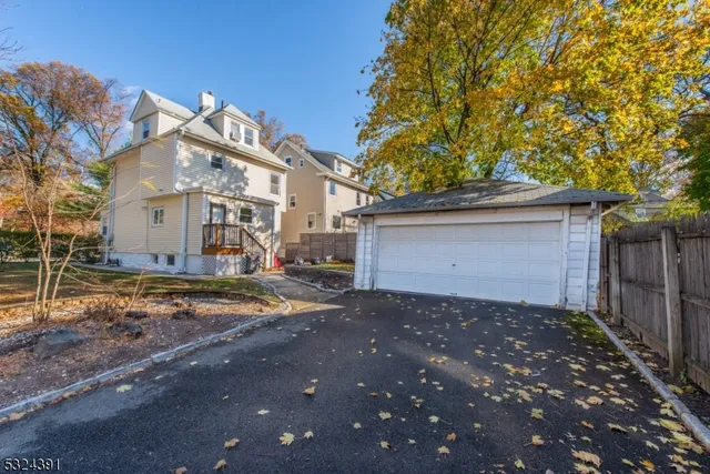 a view of a white house next to a yard and large trees