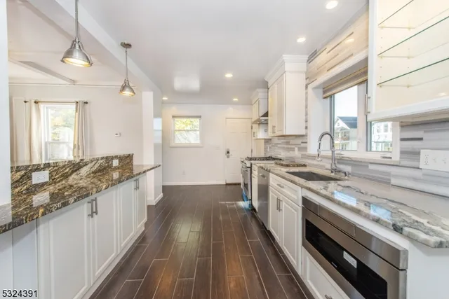a large kitchen with granite countertop a large stove top oven sink and cabinets