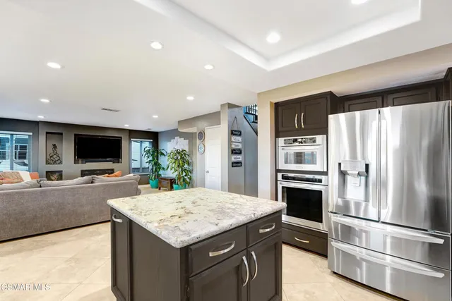 a kitchen with stainless steel appliances kitchen island granite countertop a refrigerator and a stove top oven