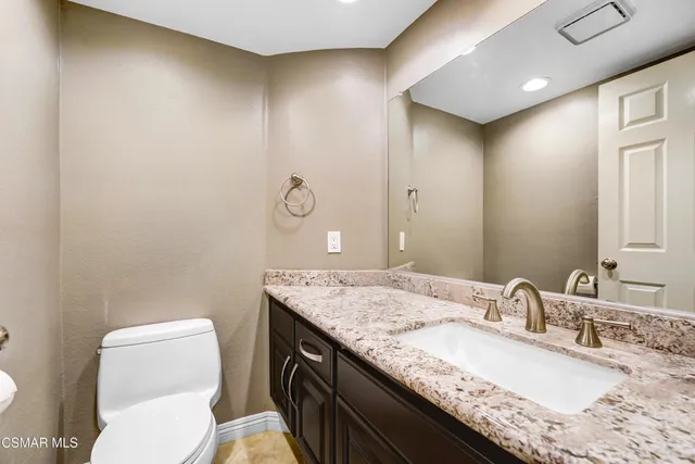 a bathroom with a granite countertop sink a toilet and a mirror