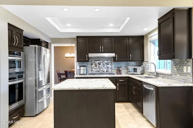 a kitchen with stainless steel appliances granite countertop a refrigerator a sink a stove a microwave and island