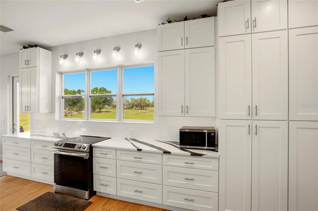 10080 Wauchula Road Myakka City, FL 34251 - Photo 13 of 55 a kitchen with stainless steel appliances white cabinets and a stove top oven
