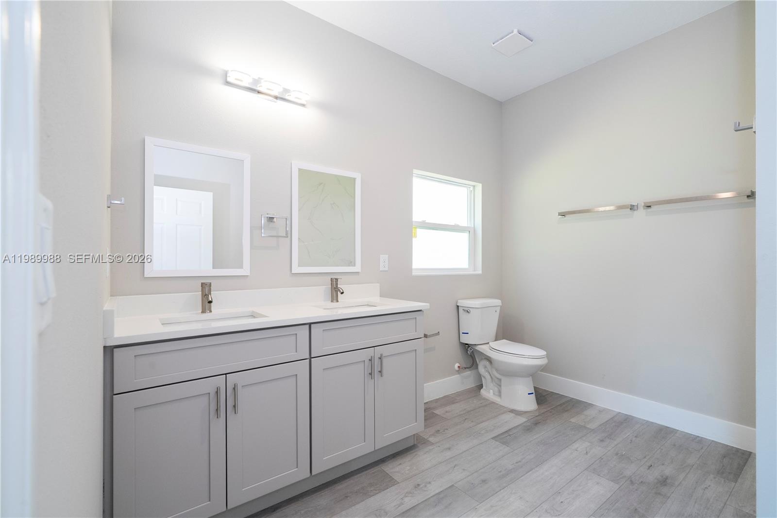 7916 Granada Road Sebring, FL 33876 - Photo 36 of 60 a bathroom with a toilet a sink a mirror and a window