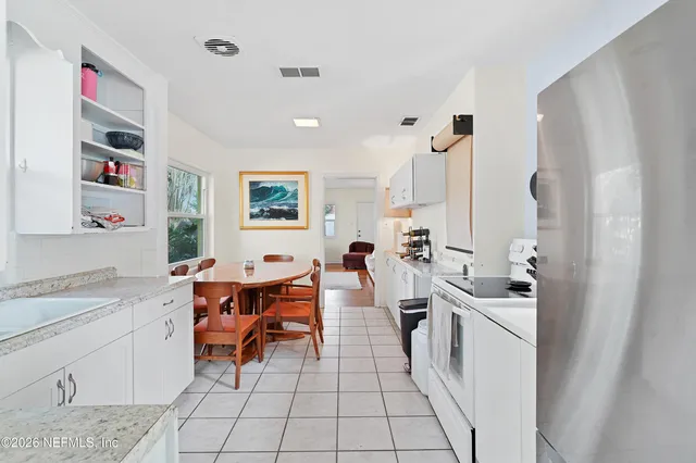 a large white kitchen with a sink and washing machine