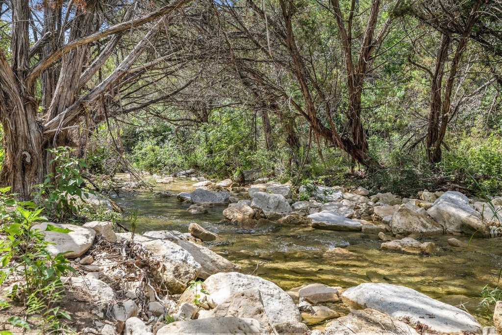 23644 Nameless Road Leander, TX 78641 - Photo 30 of 40 A tranquil, rock-strewn creek meanders through a lush, wooded landscape.
