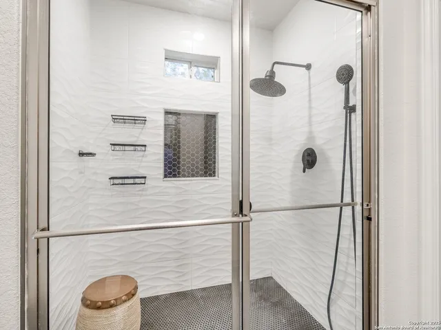 a room with stainless steel appliances kitchen island granite countertop a refrigerator a stove a sink dishwasher and white cabinets with wooden floor