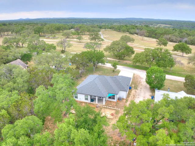 an aerial view of residential houses with outdoor space and trees