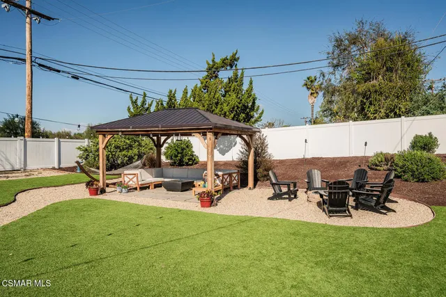 a view of a patio with table and chairs under an umbrella with a small yard