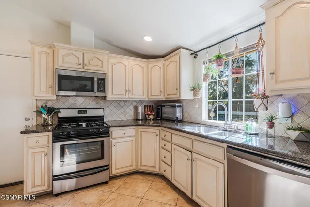 a kitchen with granite countertop a stove a sink and a microwave