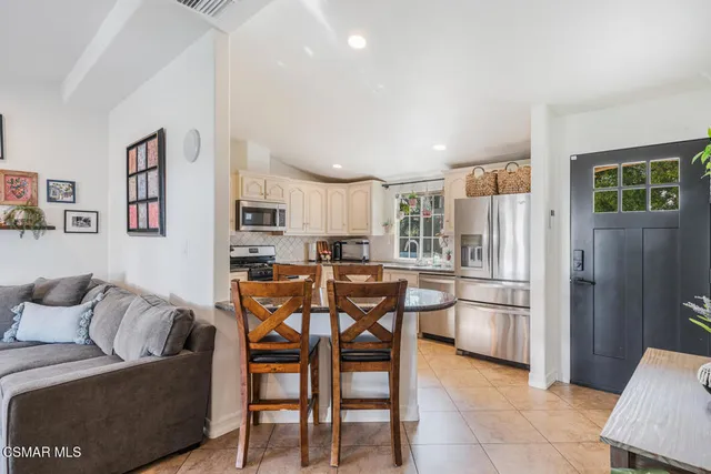 a living room with furniture a refrigerator and kitchen view