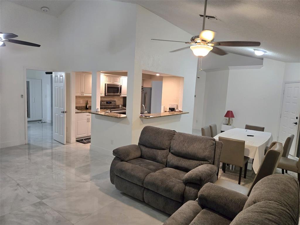 2280 Springwood Circle West Clearwater, FL 33763 - Photo 8 of 25 a living room with furniture a chandelier and a view of kitchen