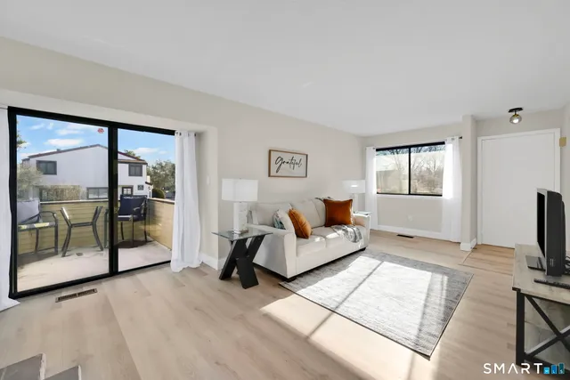 a living room with furniture a flat screen tv and a floor to ceiling window