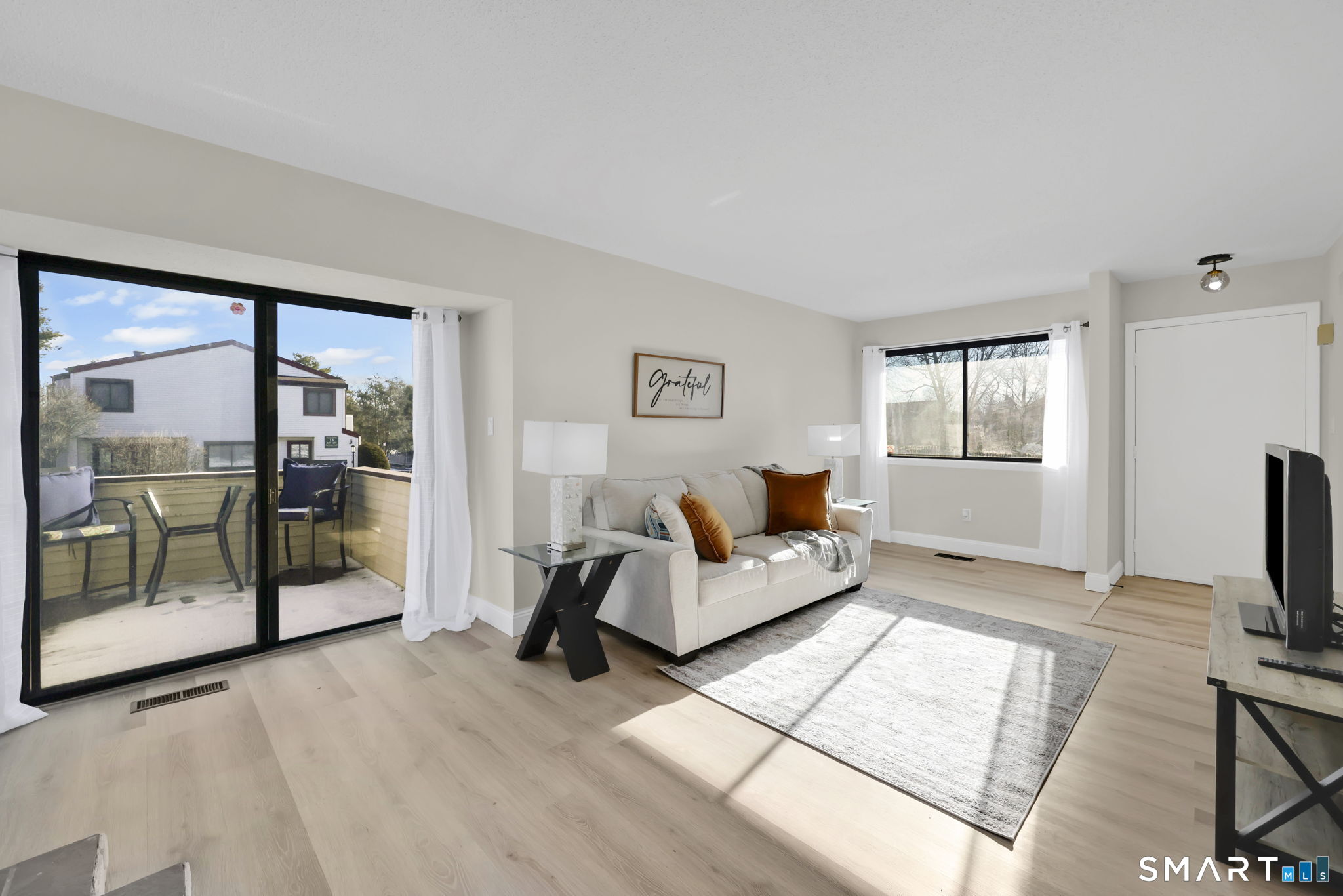 273 Cottonwood Road, Unit 273 Newington, CT 06111 - Photo 6 of 38 a living room with furniture a flat screen tv and a floor to ceiling window