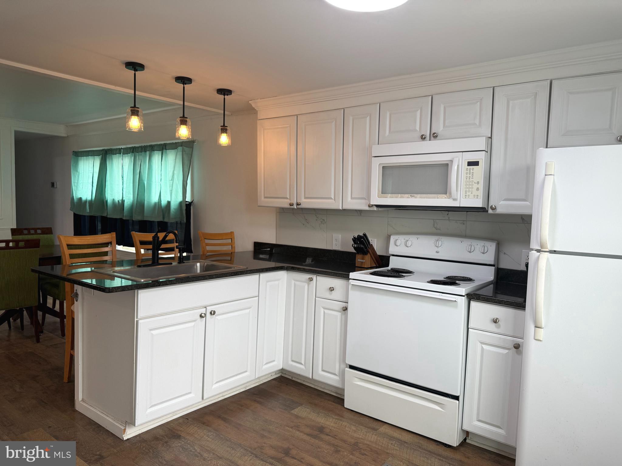 33987 Sunflower Road, Unit 3831 Lewes, DE 19958 - Photo 11 of 17 a kitchen with a sink a stove a refrigerator and white cabinets