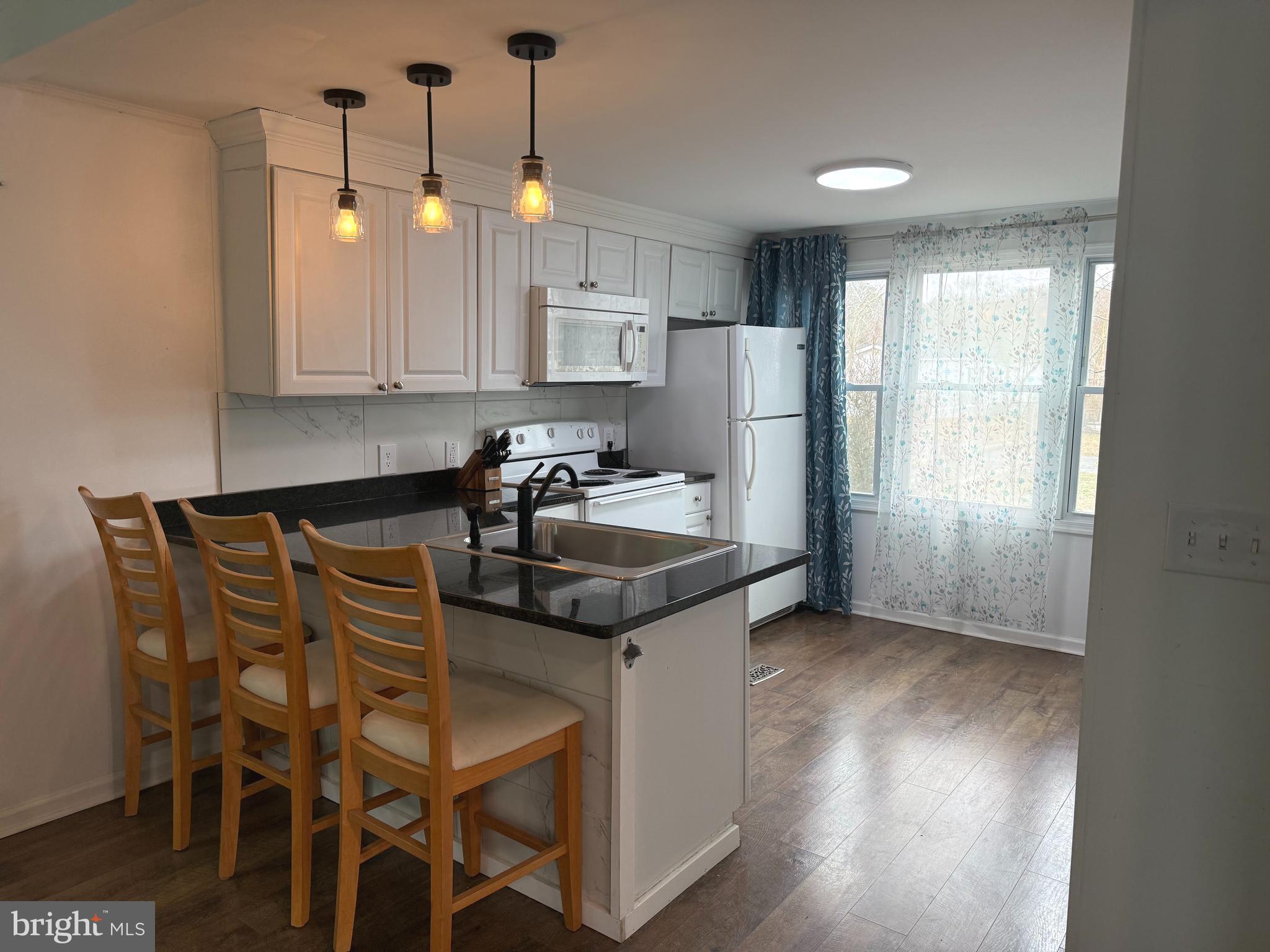 33987 Sunflower Road, Unit 3831 Lewes, DE 19958 - Photo 8 of 17 a kitchen with stainless steel appliances granite countertop a sink a stove a refrigerator and island with wooden floor