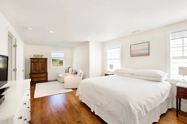 a spacious bedroom with a bed and wooden floor
