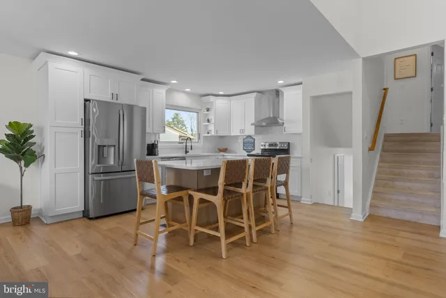 a kitchen with stainless steel appliances a refrigerator a stove a sink and white cabinets with wooden floor