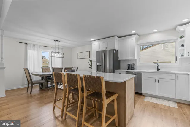 a kitchen with stainless steel appliances a dining table chairs and wooden floor
