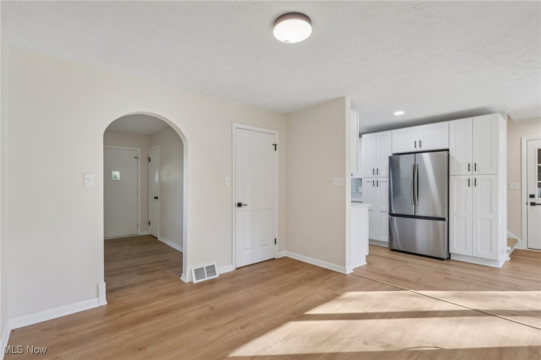 50963 Becker Road Oberlin, OH 44074 - Photo 6 of 37 Kitchen featuring white cabinetry, arched walkways, freestanding refrigerator, light wood-type flooring, and light countertops