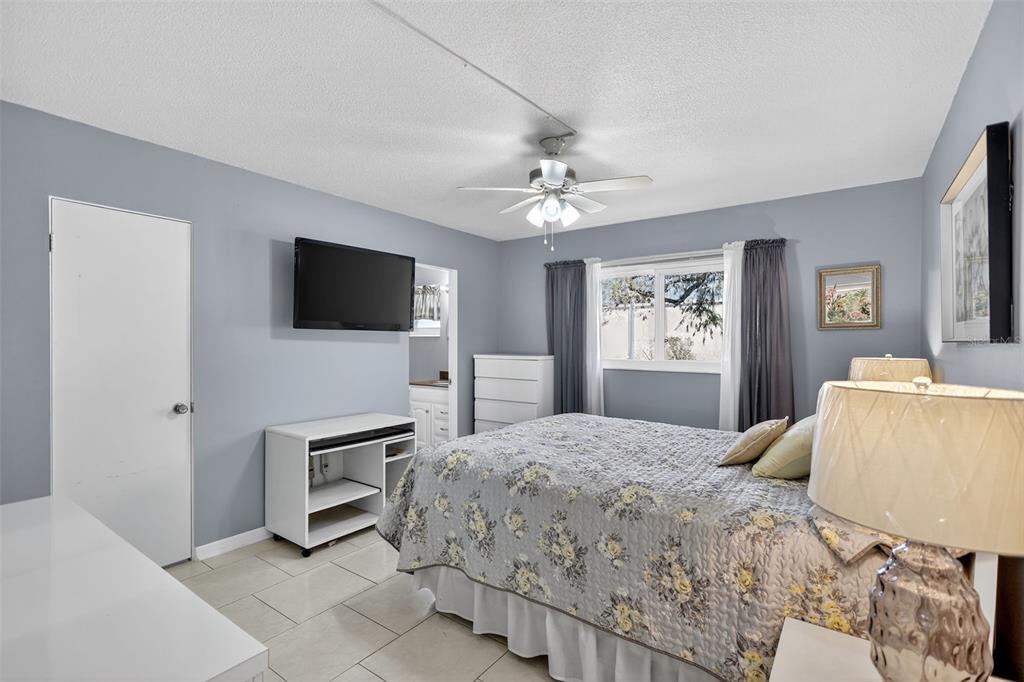 14 Strathmore Boulevard, Unit 14 Sarasota, FL 34233 - Photo 17 of 42 a bedroom with a bed a mirror on dresser and a flat screen tv