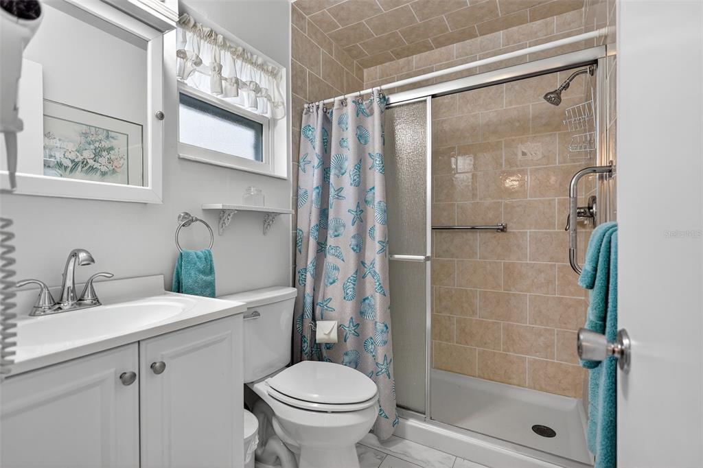 14 Strathmore Boulevard, Unit 14 Sarasota, FL 34233 - Photo 27 of 42 a bathroom with a shower sink vanity mirror and toilet