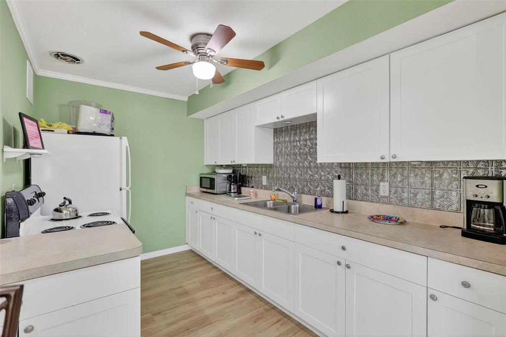 14 Strathmore Boulevard, Unit 14 Sarasota, FL 34233 - Photo 37 of 42 a kitchen with a sink dishwasher and white cabinets with wooden floor