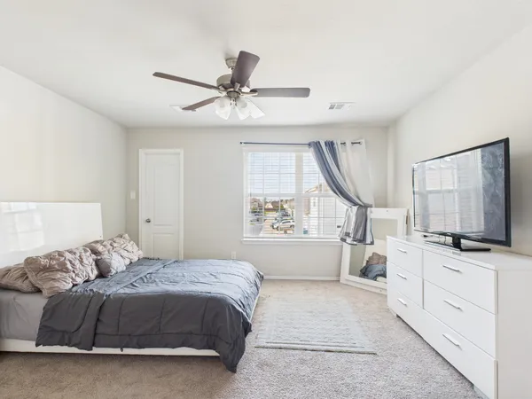 a spacious bedroom with a white bed and a flat screen tv