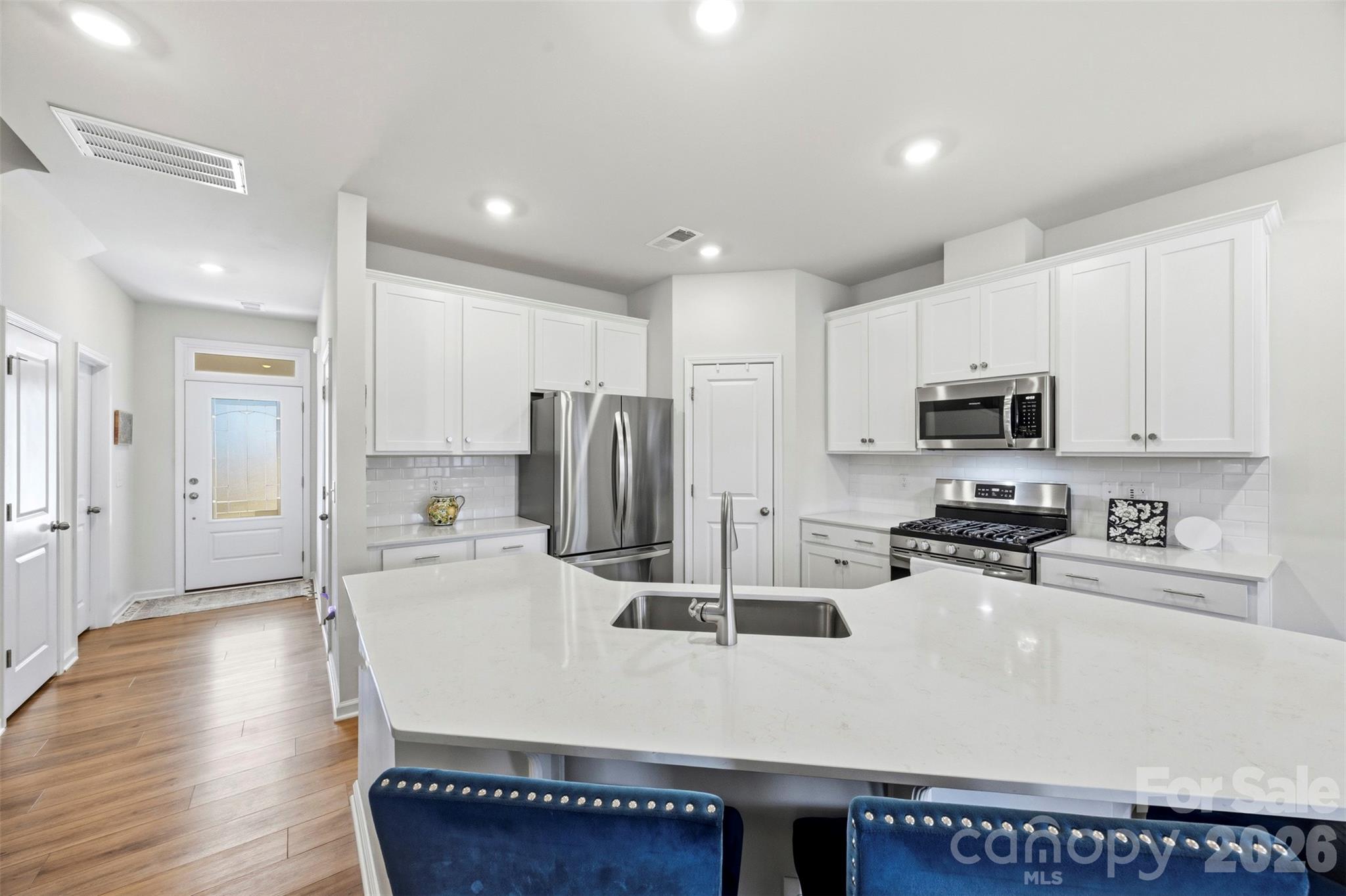 5030 Moss Pne Way Fort Mill, SC 29708 - Photo 2 of 28 a kitchen with stainless steel appliances granite countertop a sink a stove a refrigerator a microwave oven with white cabinets and wooden floor