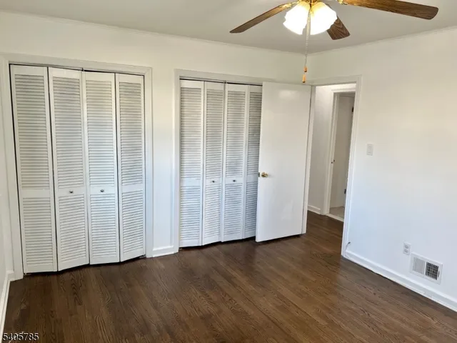 an empty room with wooden floor closet and windows