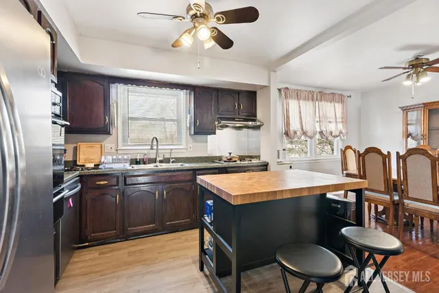 a kitchen with stainless steel appliances granite countertop a sink a stove a refrigerator cabinets and dining table