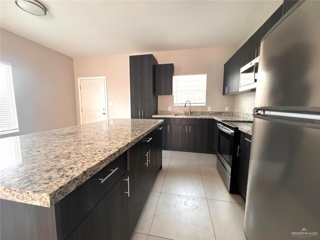 1405 Alta Vista Drive, Unit 4 Weslaco, TX 78596 - Photo 6 of 15 Kitchen with appliances with stainless steel finishes, a kitchen island, light tile patterned flooring, and light stone counters