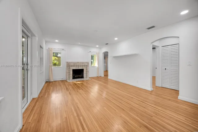 an empty room with wooden floor and fireplace