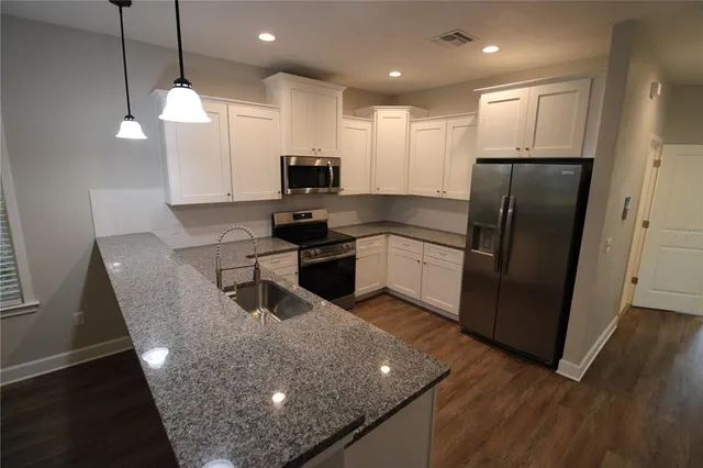 a kitchen with stainless steel appliances granite countertop a refrigerator a sink a stove a microwave a counter space and cabinets