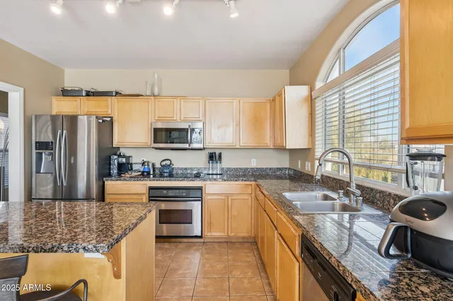a kitchen with stainless steel appliances granite countertop a sink stove refrigerator and microwave
