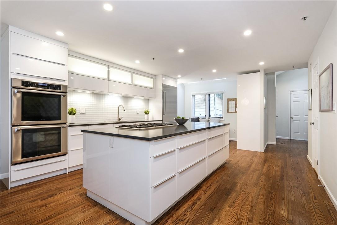 a large kitchen with stainless steel appliances a large counter top a stove and a wooden floors
