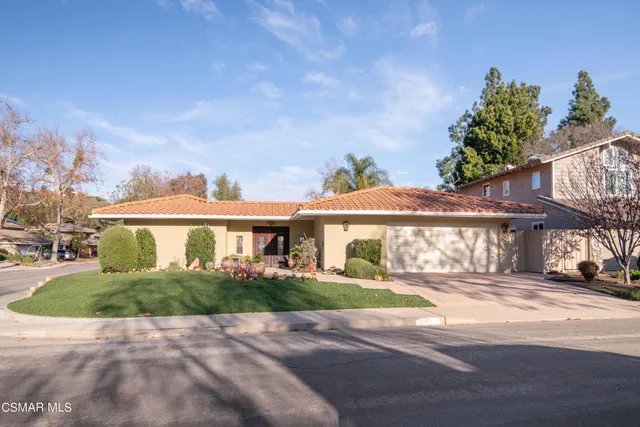 a front view of a house with a yard and potted plants